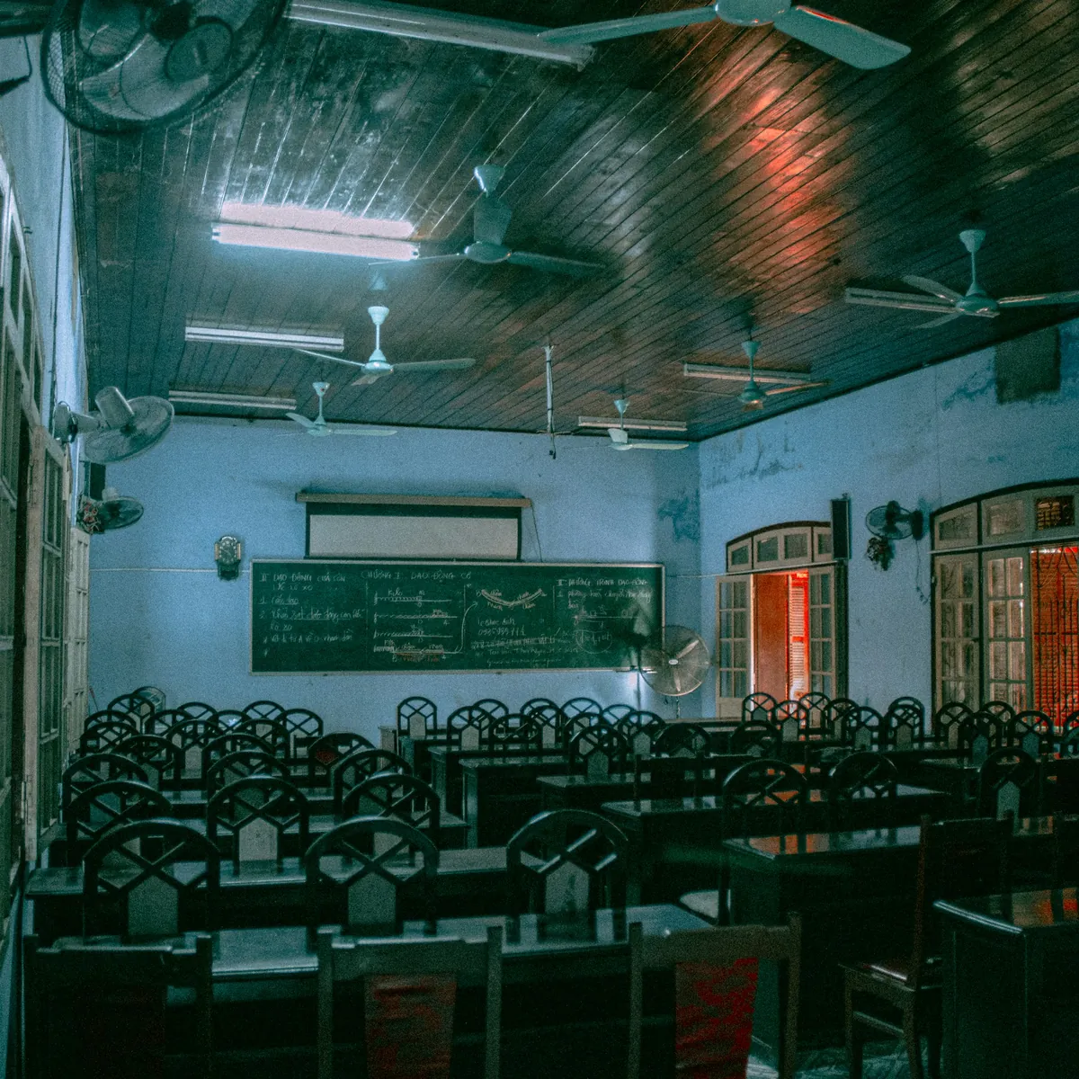 Phòng học với bàn ghế gỗ và quạt trần